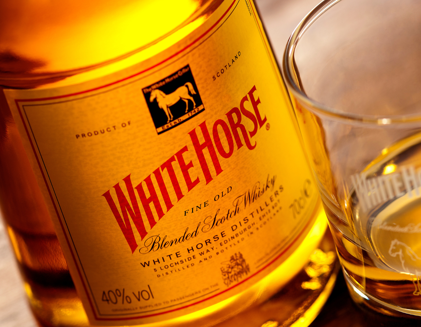Bottle of White Horse whisky on table beside glass of neat whisky