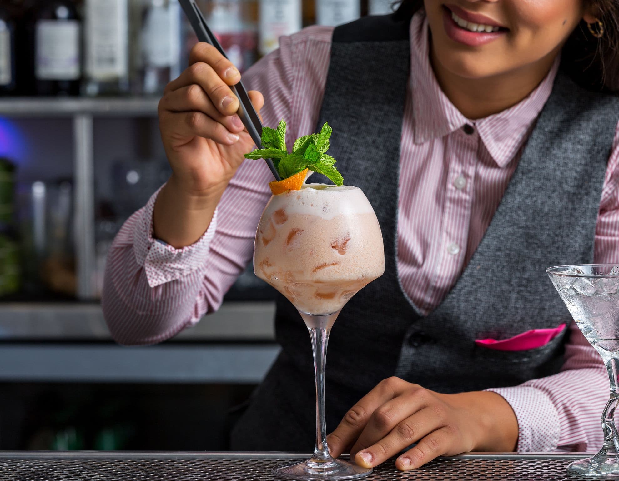 Female bartender adding straw to cocktail
