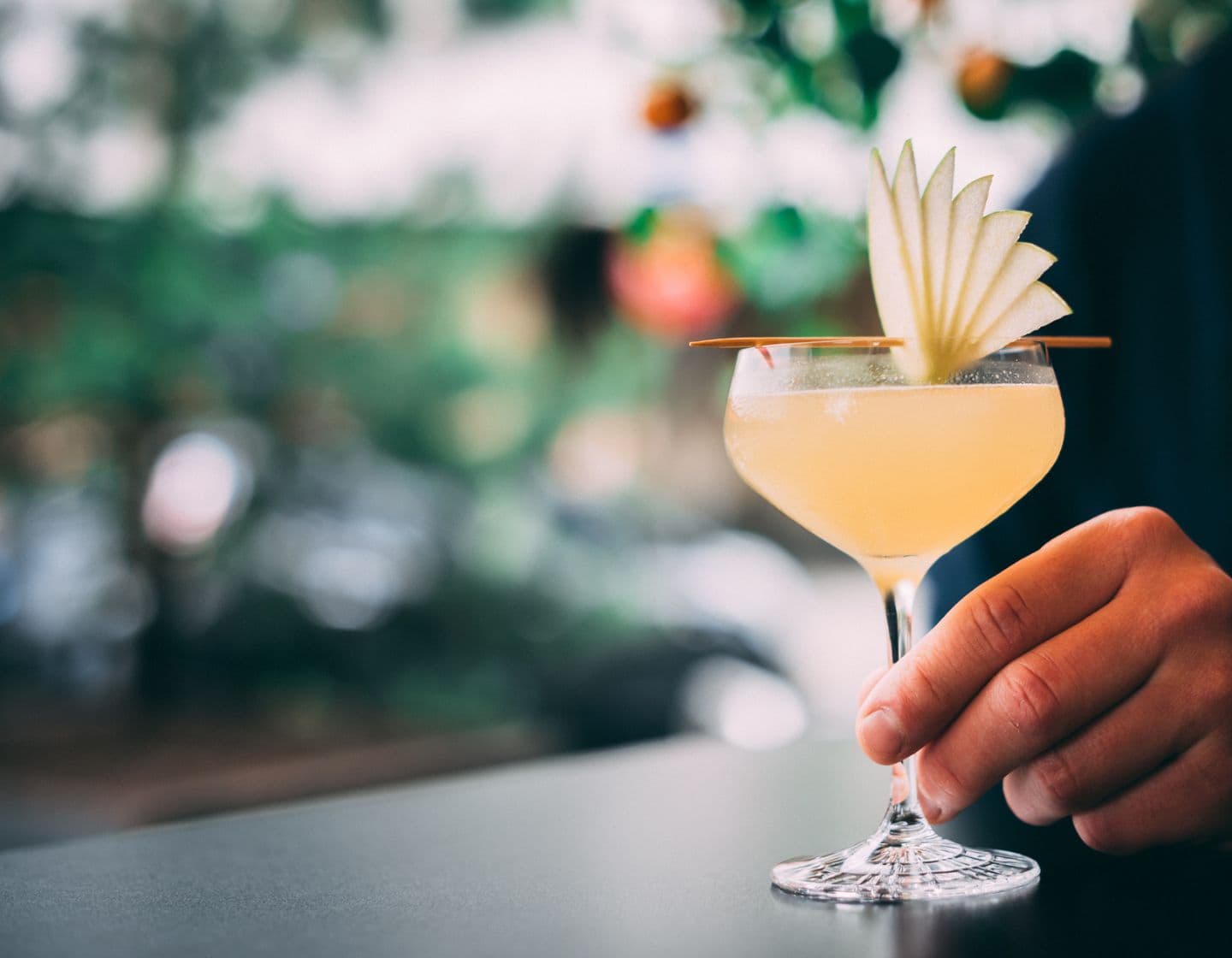  A cocktail being garnished with white florals.  