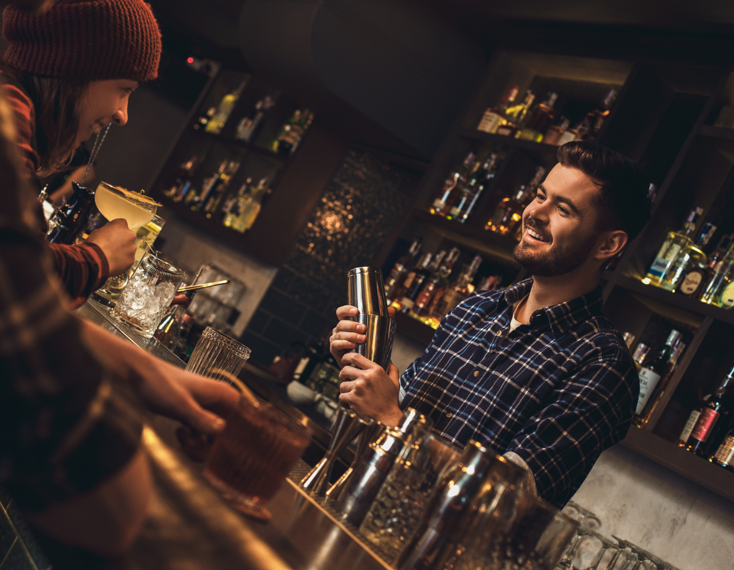 Man serving a woman a cocktail with a smile behind a bar