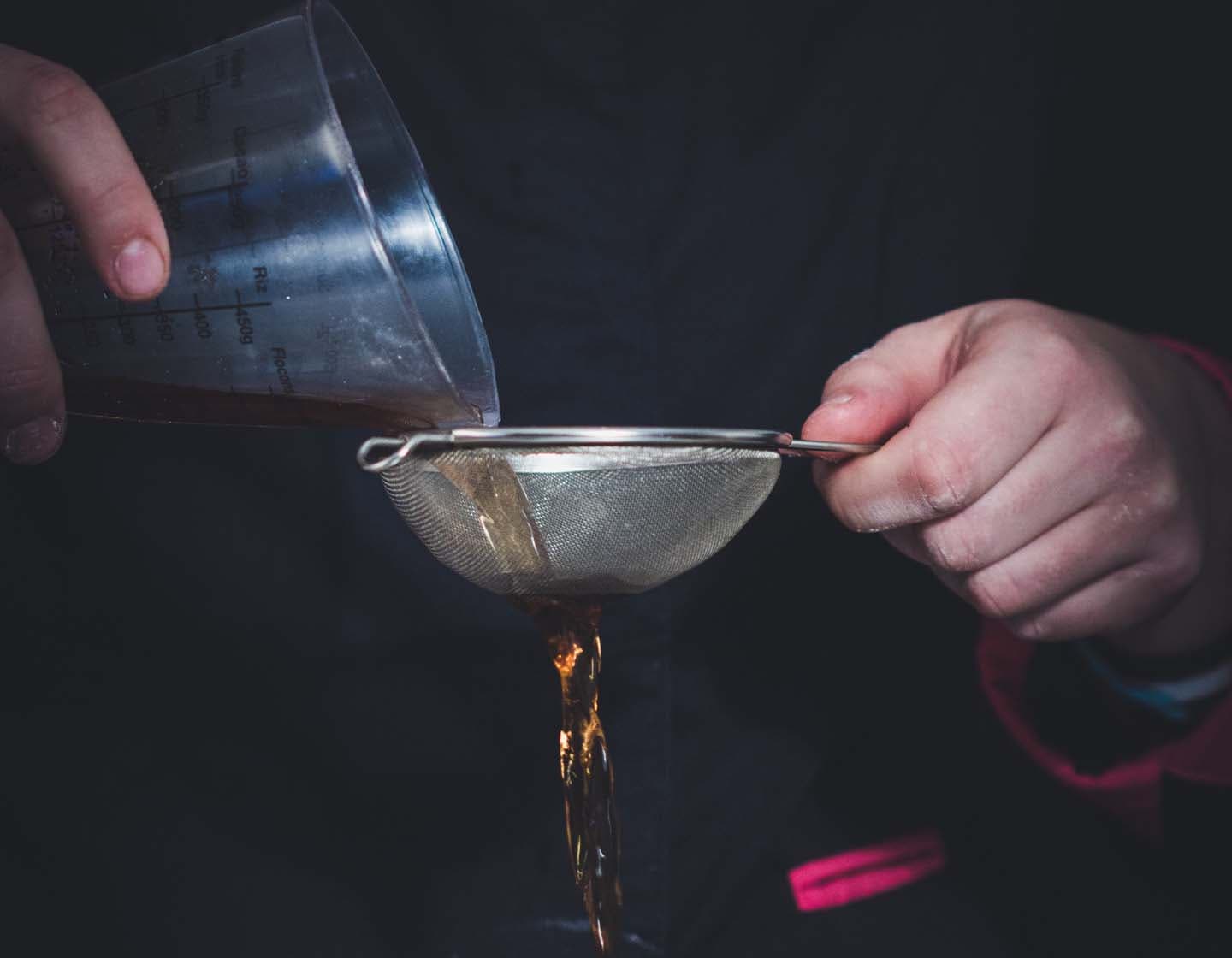 Ein Barkeeper siebt Flüssigkeit in ein Cocktailglas