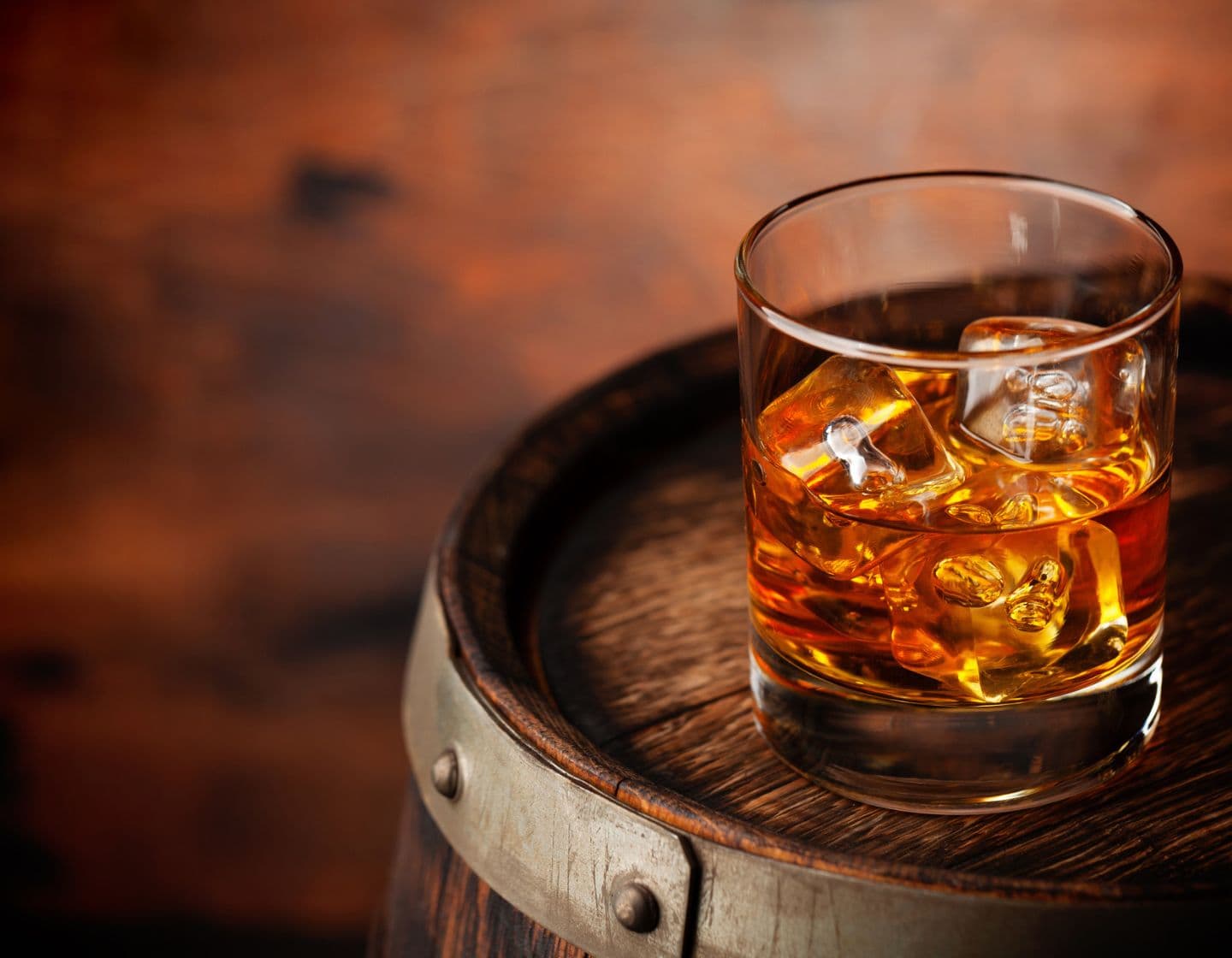 Whisky con hielo sobre un barril de madera.