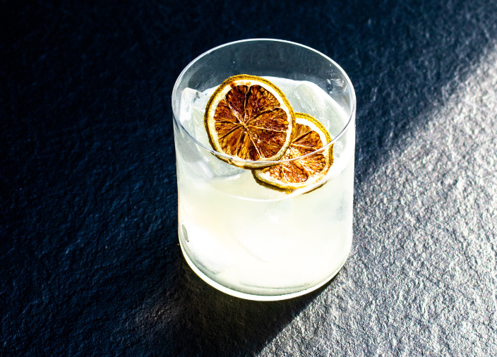 Cocktail im Whiskeyglas mit getrockneten Zitronenscheiben.