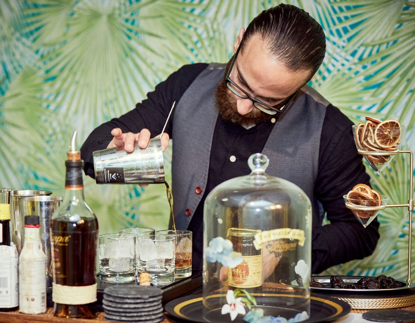 male bartender pouring cocktail into glass
