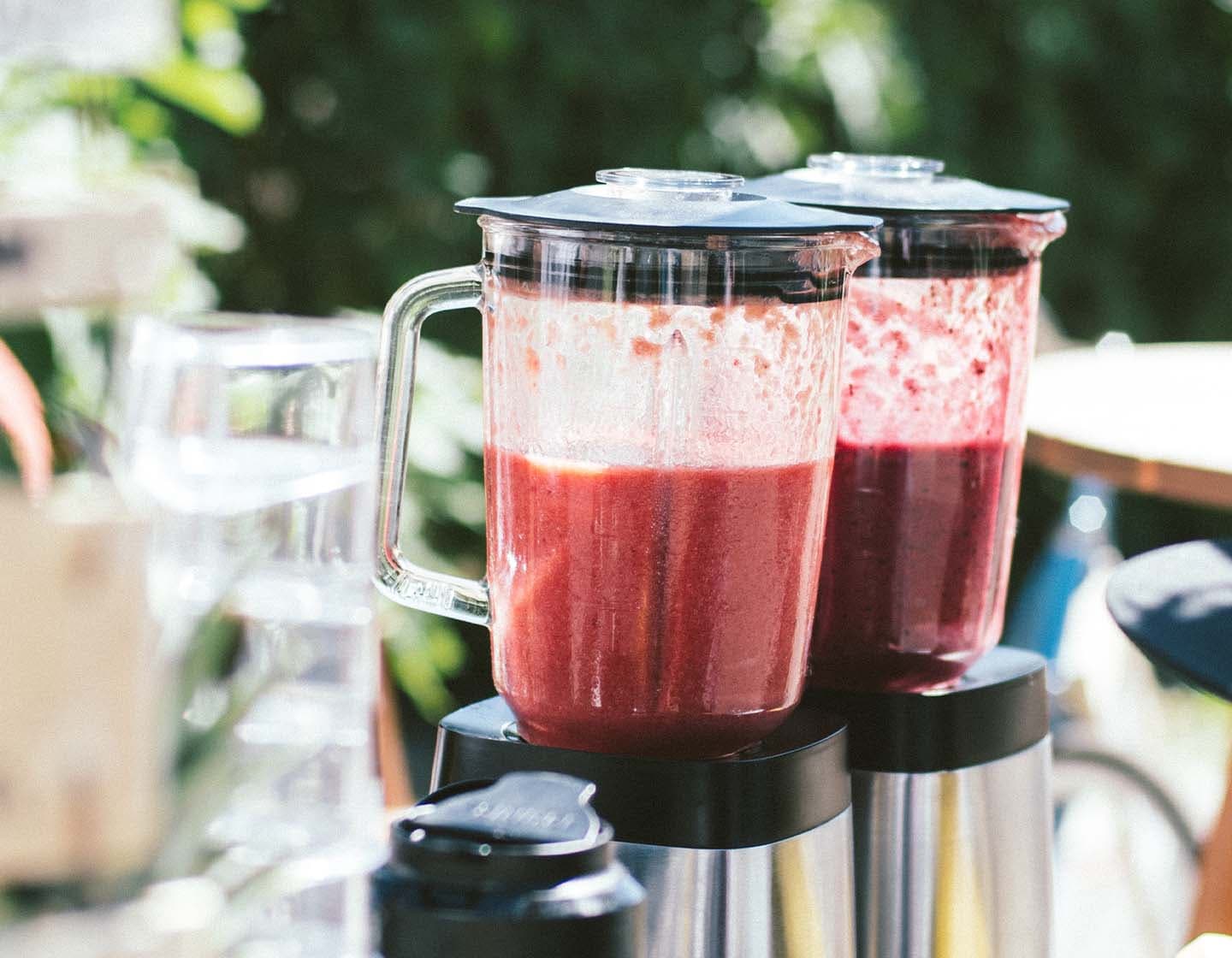 Two blenders filled with red liquid 