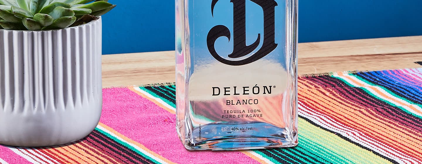 Bottle of Deleón on table with plant
