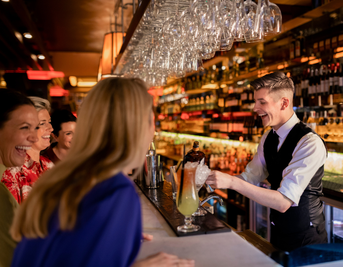 Bartender serving a customer a yellow cocktail