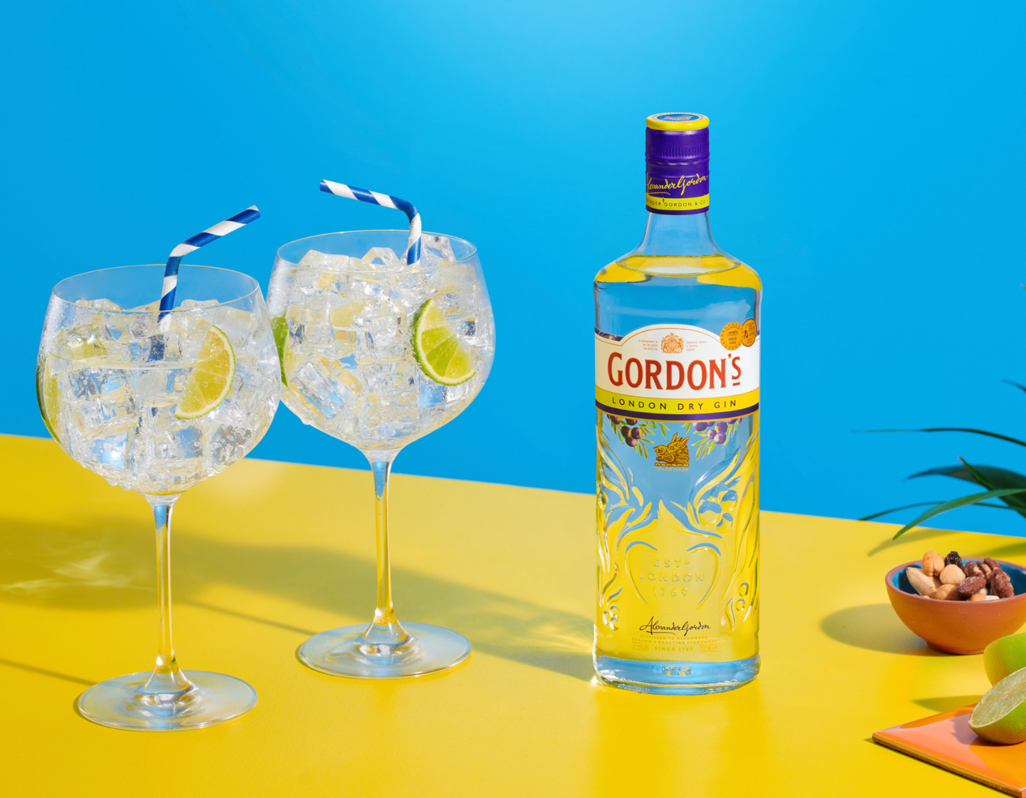 Botella de ginebra Gordon’s junto a dos copas de gin-tonic 