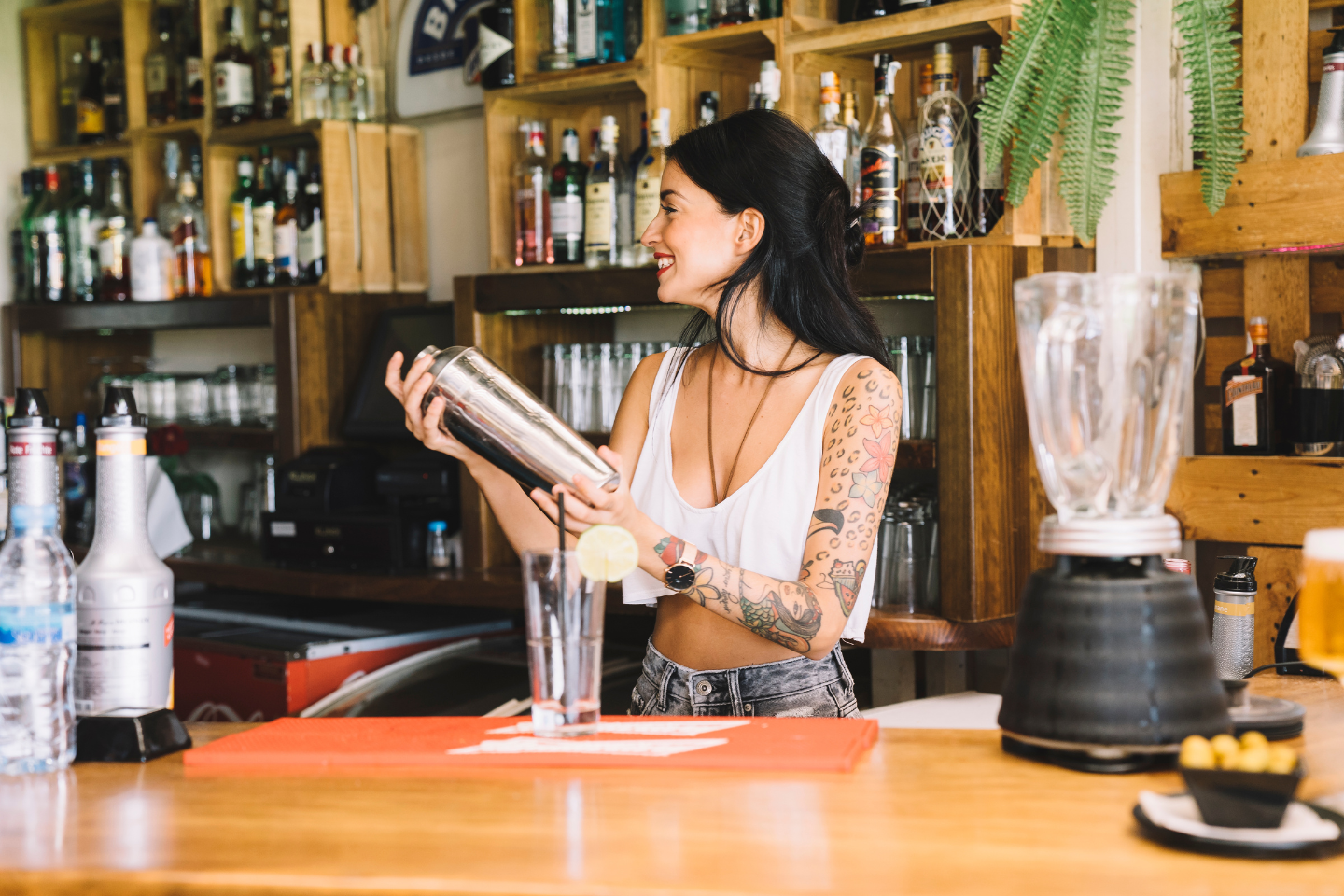 Imagem de uma bartender atrás do balcão fazendo um coquetél