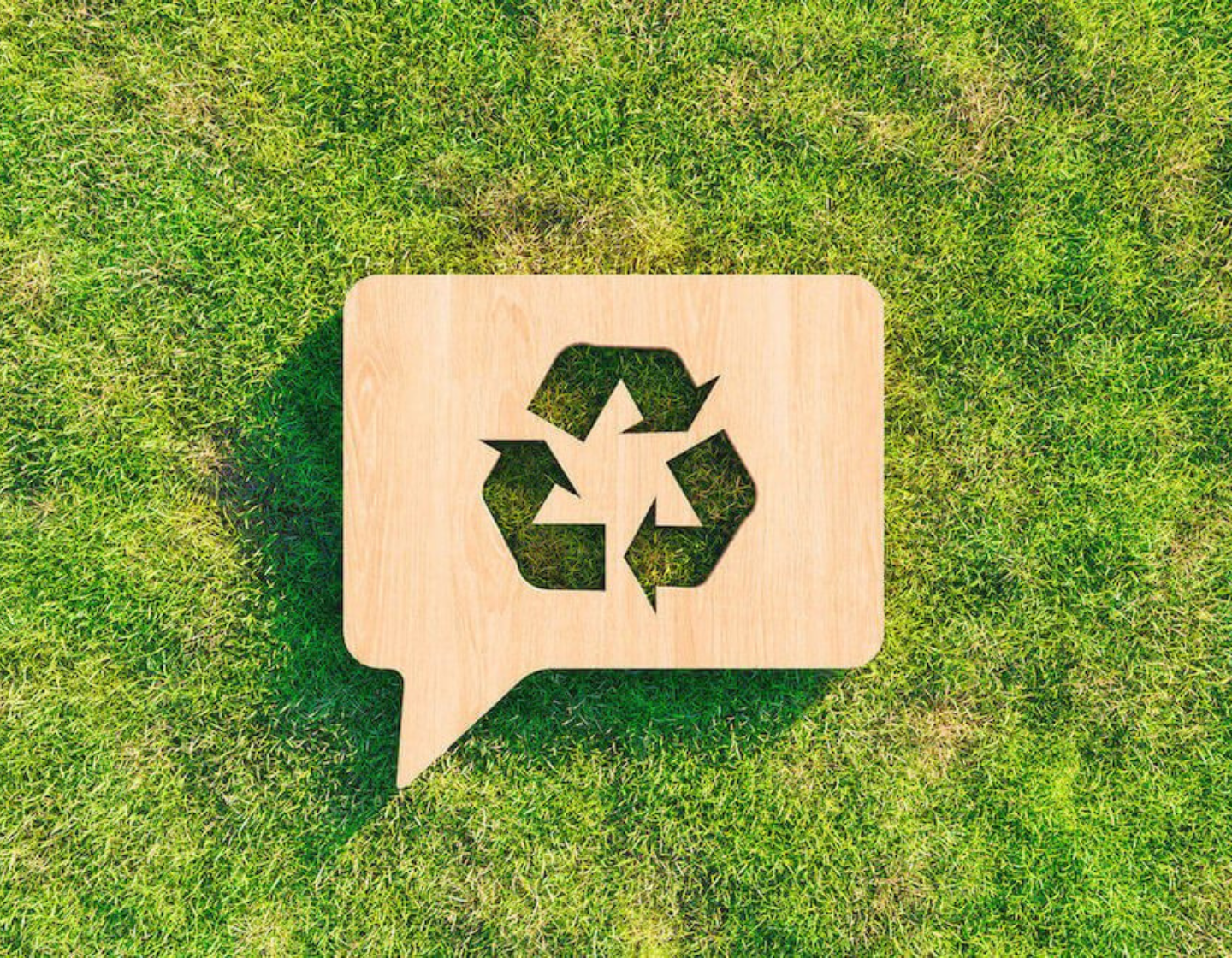 Placa de reciclagem de madeira sobre grama verde