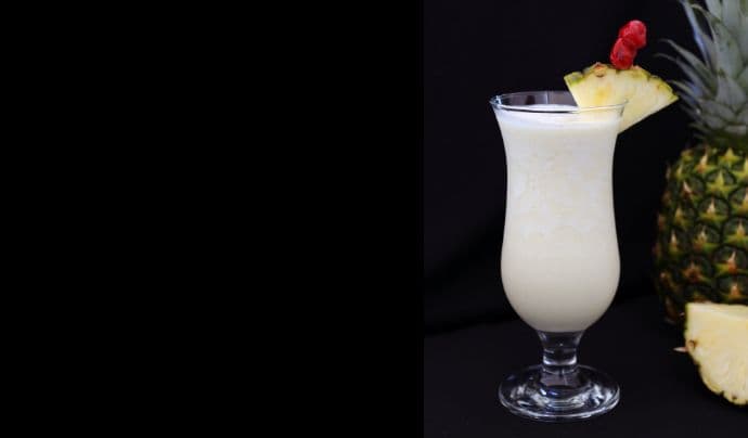 Cuban breeze cocktail on a black background by a pineapple