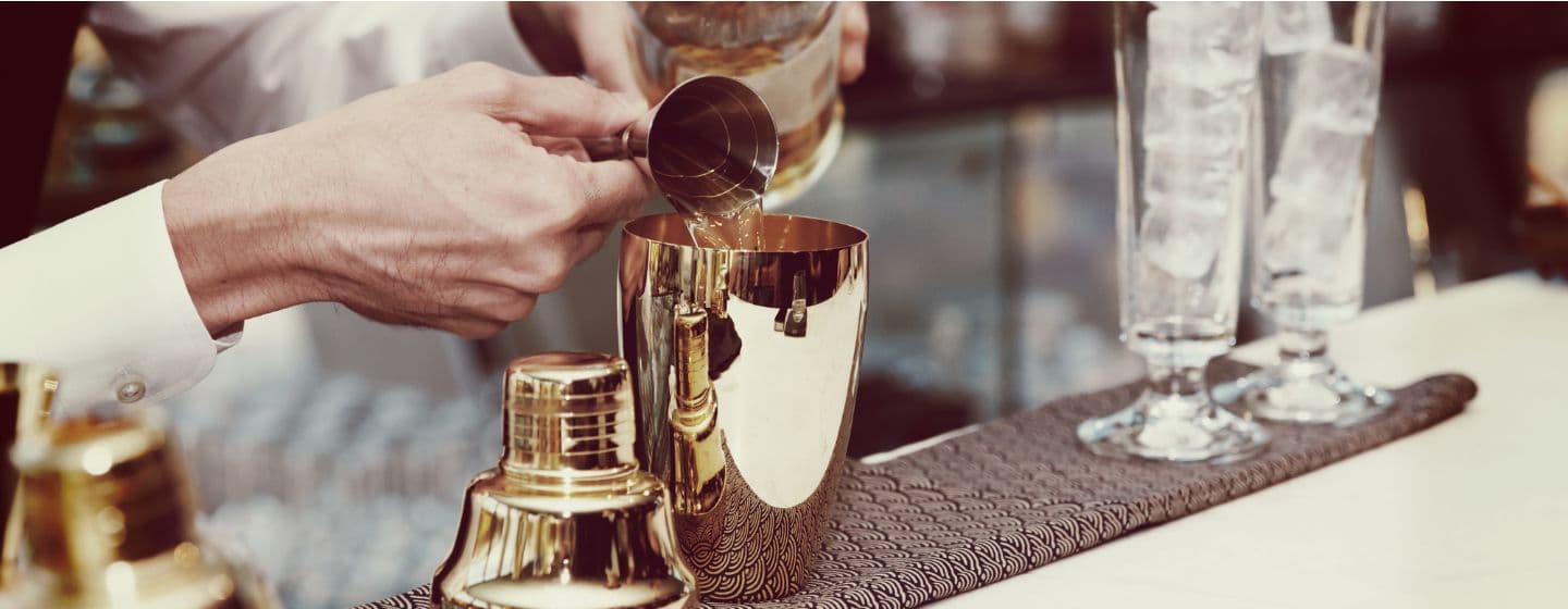 Imagem de um bartender colocando a bebida na coqueteleira 