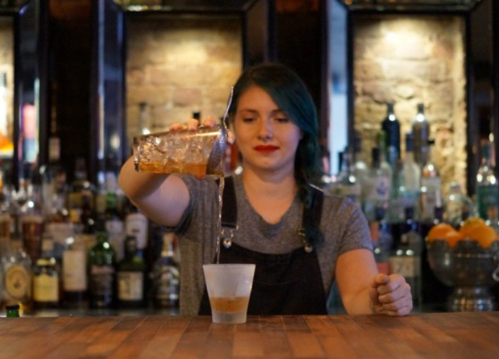 Eine Barkeeperin gießt Getränk ein