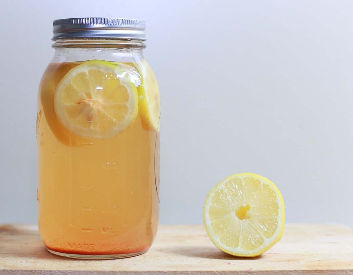 Um frasco de vidro cheio de líquido e limão. 