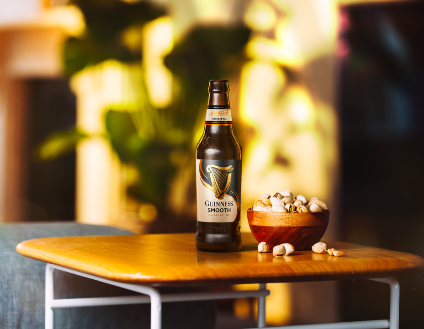 Botellín de Guinness Smooth sobre una mesa junto a un bol de palomitas 