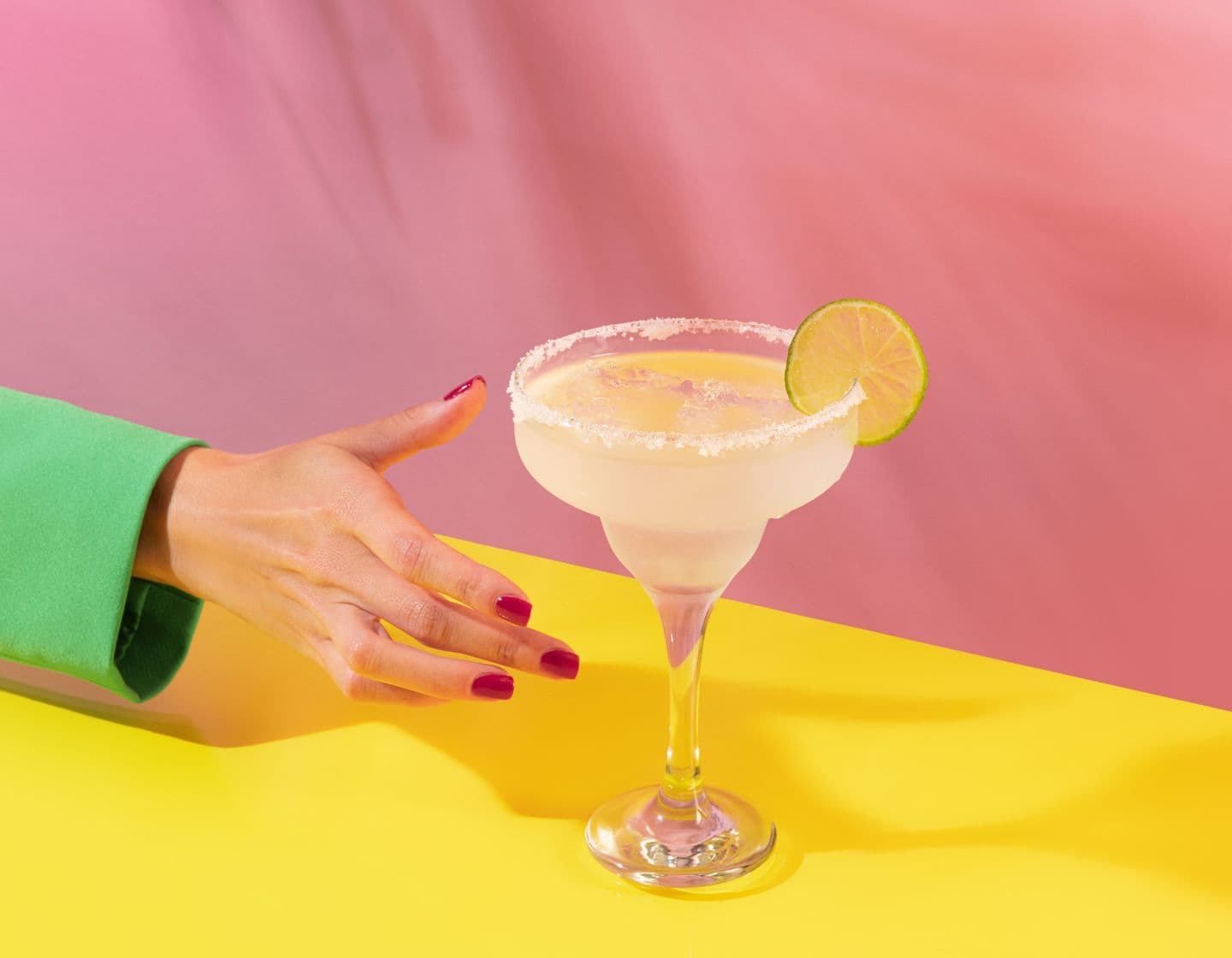 Una mano de mujer alcanzando una bebida clásica de margarita 
