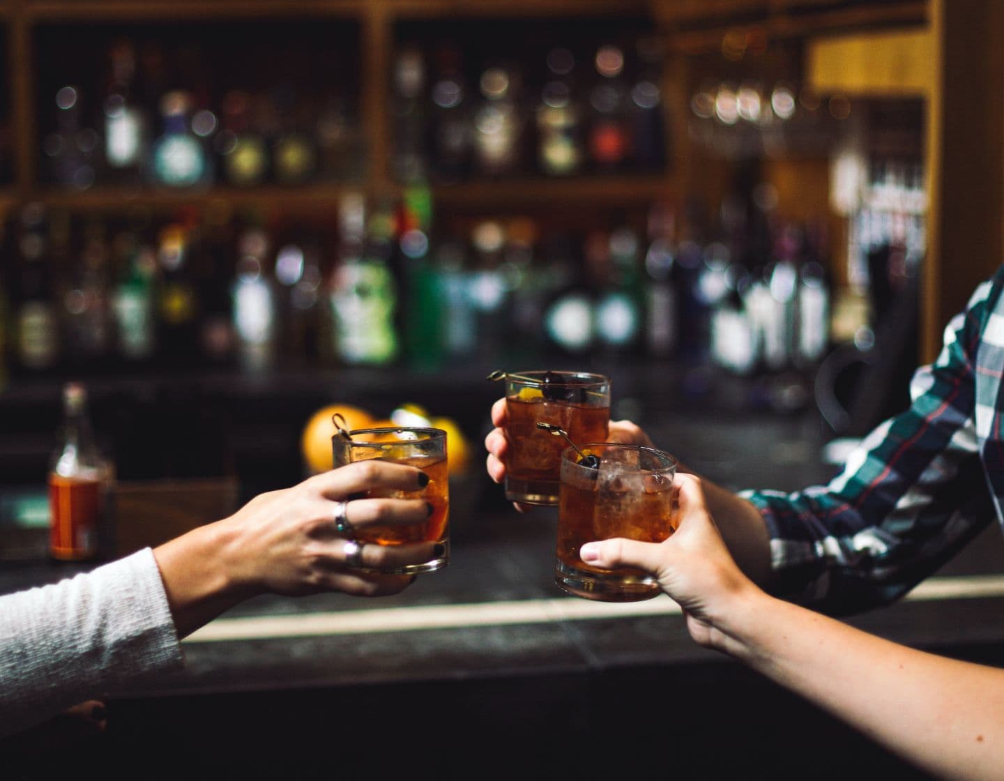 Three people clinking their whiskey cocktails 
